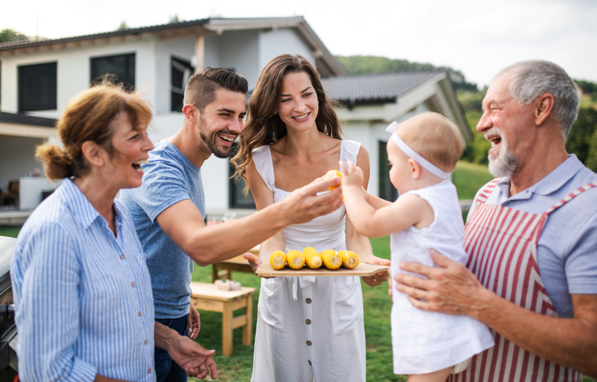 Three generations of a family grilling and sharing food at a backyard barbecue